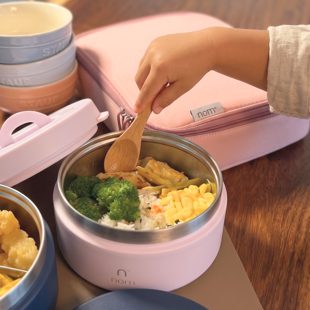 Hand filling the nom insulated food jar through its wide mouth opening