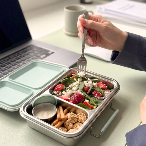 Stainless steel bento lunch box with seafoam green lid used for office meal prep, healthy lunch with salad and snacks, nom duo